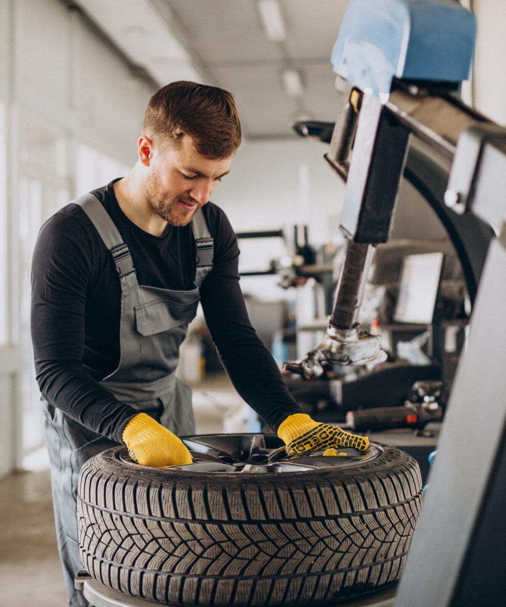 Car mechanic changing wheels in car
